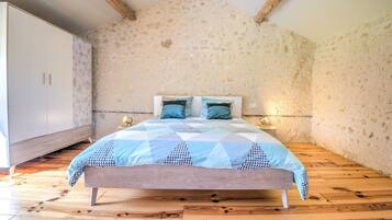 Ein Schlafzimmer mit einem Bett, Holzboden, Steinwand und einem Kleiderschrank.