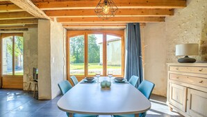 A dining area with a large table, chairs, a chandelier, and a view of the outdoors. - Gîte Le Pigeonnier with Shared Pool, Wi-Fi, and Air Conditioning (Chassaignes)