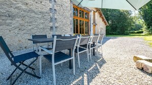 Un espace de restauration en plein air avec une table et des chaises, un mur en pierre et une porte en bois.