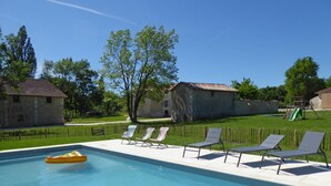 Una piscina con sillas de descanso y un pequeño bote inflable.