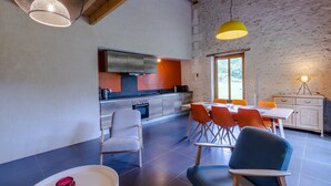 Una cocina moderna con comedor, que presenta una pared de piedra, vigas de madera y mobiliario contemporáneo.