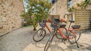 En byggnad av sten med en innergård belagd med grus, en cykel och ett litet träd.