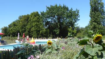 A pool area with a wooden fence, surrounded by various plants and flowers.