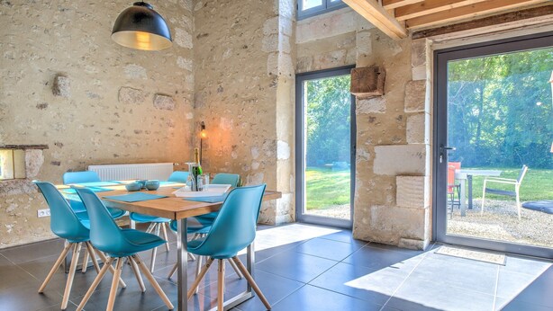 Un comedor con pared de piedra, techo de madera y vistas al exterior.