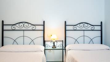 Habitación doble con dos camas, una mesita de noche con lámpara y un espejo.