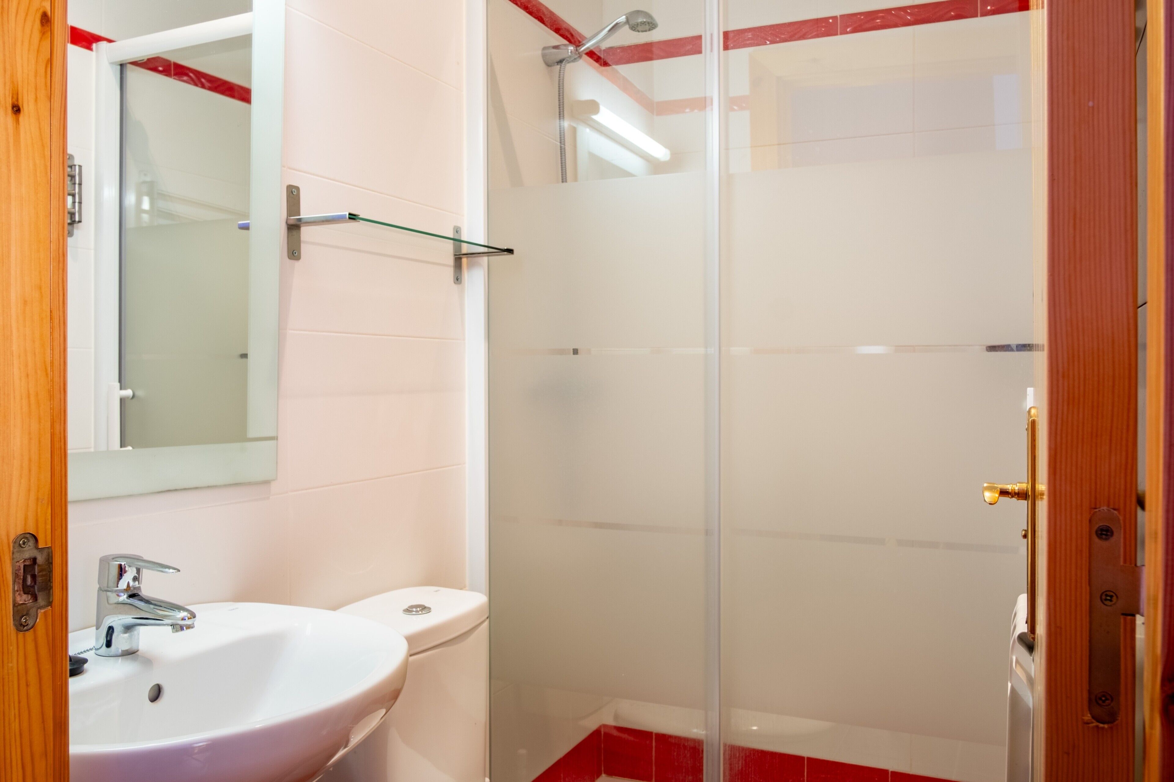 Une salle de bain avec un lavabo blanc, des toilettes et une cabine de douche en verre.