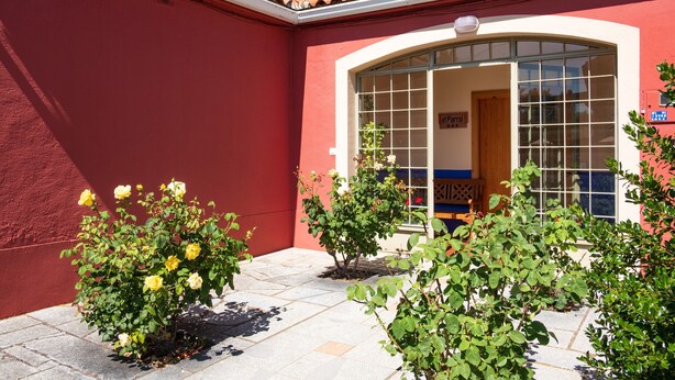A red building with a tiled roof, a large arched window, and a sign that reads 'el Parral.' - Holiday Home 'El Parral' with Mountain Views, Shared Terrace and Wi-Fi (La Rinconada de la Sierra)