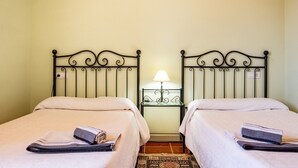 A room with two beds, a nightstand with a lamp, and a painting on the wall. - Holiday Home 'El Parral' with Mountain Views, Shared Terrace and Wi-Fi (La Rinconada de la Sierra)