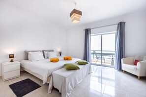 Une chambre moderne avec un lit, des tables de chevet, un bureau, une chaise et une vue sur le balcon.