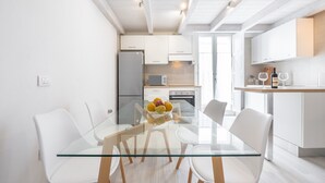 Eine moderne Küche mit weißen Schränken, einem Glastisch und einer Obstschale.