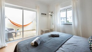 A bedroom with a bed, a hammock, a window, and a view of the outside. - Holiday Home 'Casa Cláudia - Cond  Atalaia' with Shared Pool, Private Terrace and Wi-Fi (Lagos)