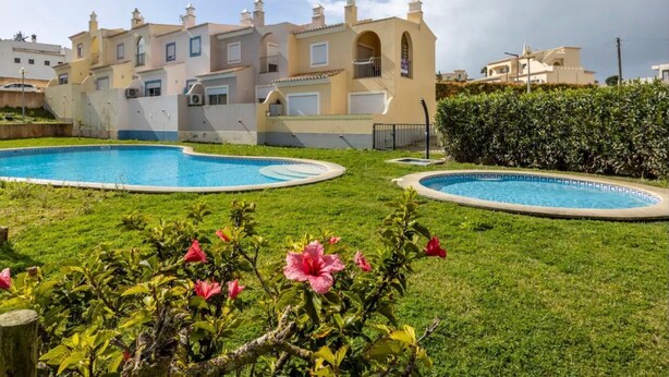 Un edificio residencial con piscina y césped bien cuidado.
