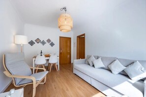 A room with a sofa, chairs, a dining table, a hanging light fixture, and decorative wall art. - Holiday Home 'Casa Cláudia - Cond  Atalaia' with Shared Pool, Private Terrace and Wi-Fi (Lagos)