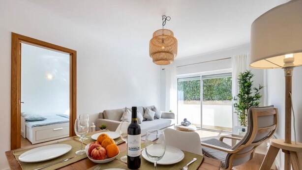 A dining area with a table set for two, a bottle of wine, and a bowl of fruit. - Holiday Home 'Casa Cláudia - Cond  Atalaia' with Shared Pool, Private Terrace and Wi-Fi (Lagos)