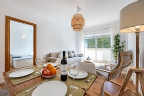 A dining area with a table set for two, a bottle of wine, and a bowl of fruit. - Holiday Home 'Casa Cláudia - Cond  Atalaia' with Shared Pool, Private Terrace and Wi-Fi (Lagos)