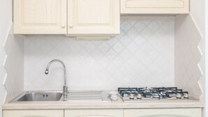 Una cocina con un lavamanos, grifo, estufa y armarios.