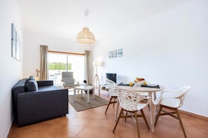 Una sala moderna con sofá, mesa de comedor, sillas y televisor.