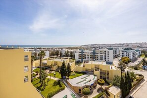 A residential area with modern buildings, a clear sky, and a distant view of the sea. - Apartment 'Casa Cláudia - Cond Do Mar' with Sea View, Shared Pool and Wi-Fi (Lagos)