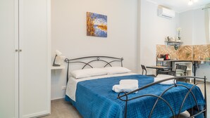 A bedroom with a bed, a desk, a chair, a shelf with toiletries, and a painting on the wall. - Apartment 'Al Nitta 2' with Wi-Fi and Air Conditioning (Catania)
