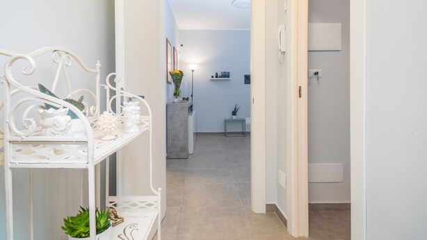 A hallway with a white metal shelf, a potted plant, and a door leading to another room. - Apartment 'Al Nitta 2' with Wi-Fi and Air Conditioning (Catania)