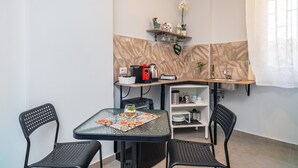 A compact kitchen with a dining table, chairs, a coffee machine, and a shelf with decorative items. - Apartment 'Al Nitta 2' with Wi-Fi and Air Conditioning (Catania)