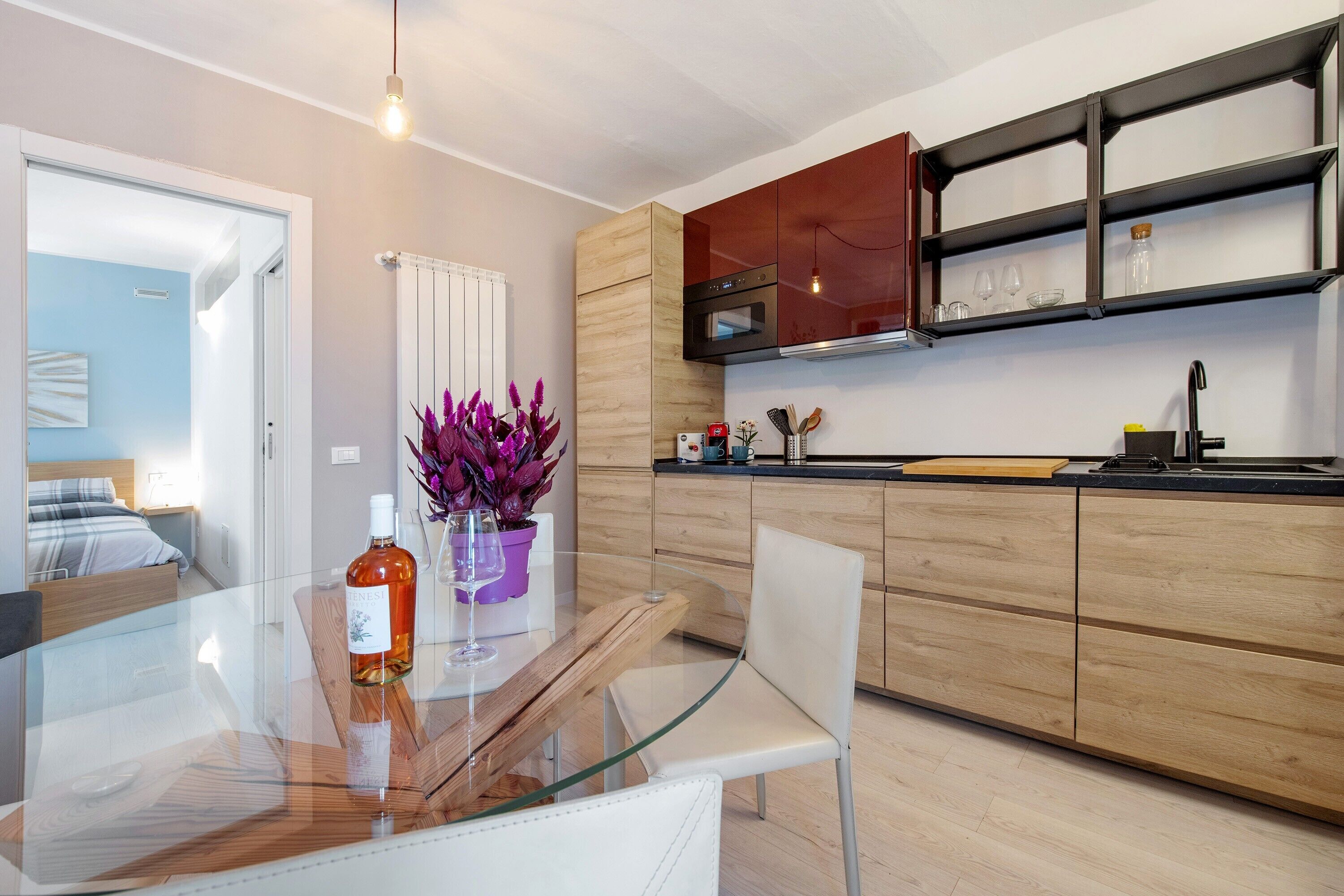 Una cocina moderna con una mesa de comedor de vidrio, armarios de madera y un horno empotrado.