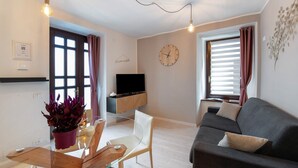 Un salon moderne avec un canapé, un téléviseur, une table en verre et une plante en pot.