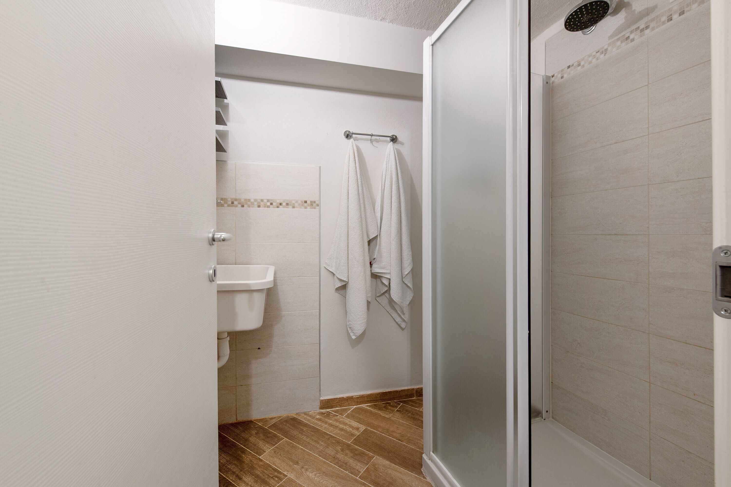Un baño con ducha, lavamanos y toallas.