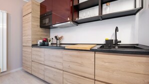 Une cuisine moderne avec des meubles en bois, un plan de travail noir, un évier en acier inoxydable et un four encastré.