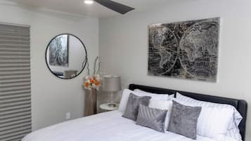 Une chambre à coucher avec un lit, un miroir rond, une lampe et une œuvre d’art représentant une carte du monde accrochée au mur.