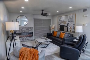 Una sala de estar moderna con chimenea, un conjunto de sofás, una mesa de centro y una lámpara de pie.