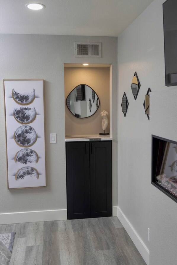 A hallway with a framed artwork of moons, a round mirror, and decorative wall pieces.