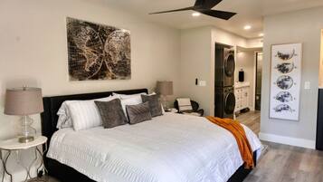 A bedroom with a large bed, a ceiling fan, and a wall-mounted artwork.