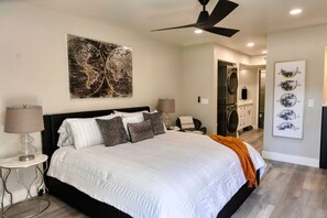 Quarto com uma cama grande, um ventilador de teto e uma obra de arte na parede.