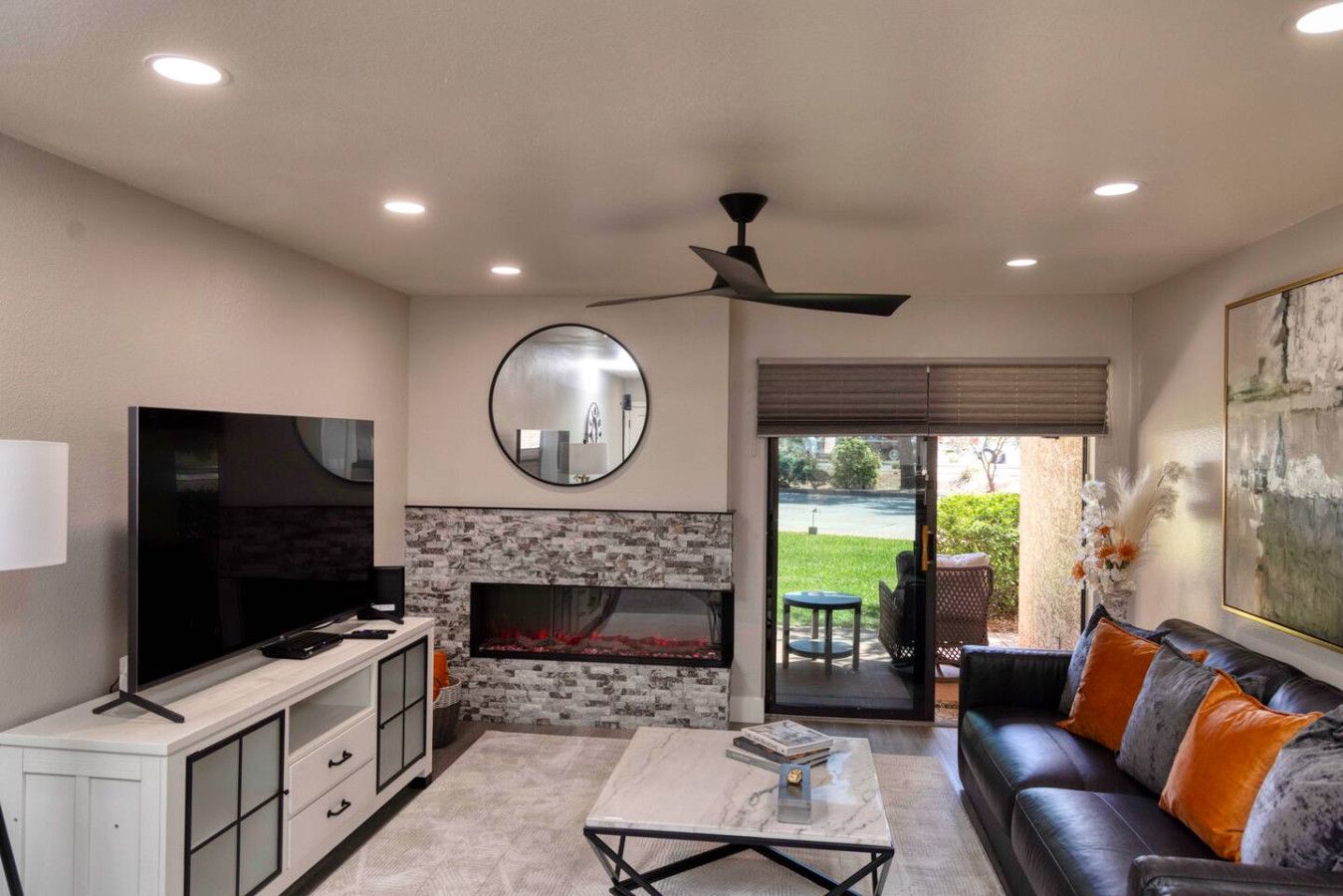 A living room with a TV, fireplace, sofa, and a ceiling fan.