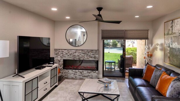 A living room with a TV, fireplace, sofa, and a ceiling fan.