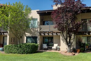A two-story building with a patio area featuring outdoor furniture and potted plants. - Sultry Sedona Getaway  (Sedona)