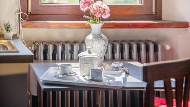 A table with a tray containing a teapot, cups, and a vase with flowers. - Apartment 'Il Flauto Magico' with Mountain View, Shared Garden and Wi-Fi (Serralunga d'Alba)