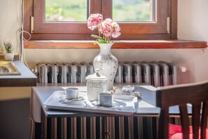 A table with a tray containing a teapot, cups, and a vase with flowers. - Apartment 'Il Flauto Magico' with Mountain View, Shared Garden and Wi-Fi (Serralunga d'Alba)