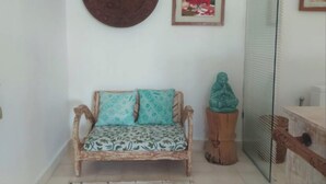 A room with a wicker sofa, a round wall decoration, and a framed picture. - VILLA BELLA SESEH (Cemagi)