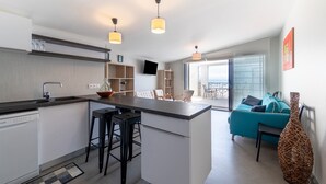 A modern kitchen with a central island, bar stools, a built-in dishwasher, and a dining area with a sofa and chairs. - Apartment 'Le Rêve 210' with Shared Pool, Wi-Fi, and Air Conditioning (La Tranche-sur-Mer)