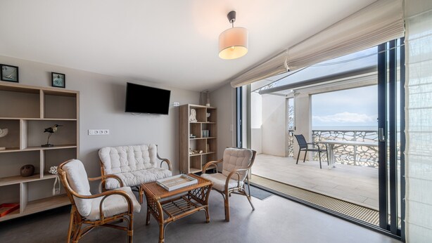 A modern living room with wicker furniture, a flat-screen TV, and a balcony with a view. - Apartment 'Le Rêve 210' with Shared Pool, Wi-Fi, and Air Conditioning (La Tranche-sur-Mer)
