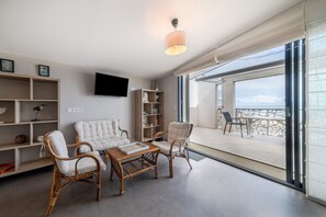 A modern living room with wicker furniture, a flat-screen TV, and a balcony with a view. - Apartment 'Le Rêve 210' with Shared Pool, Wi-Fi, and Air Conditioning (La Tranche-sur-Mer)
