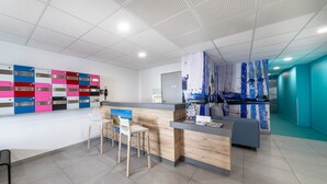 A modern reception area with a counter, bar stools, and colorful lockers. - Apartment 'Le Rêve 210' with Shared Pool, Wi-Fi, and Air Conditioning (La Tranche-sur-Mer)