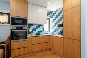 Una cocina moderna con armarios de madera, microondas, horno y salpicadero de azulejos.