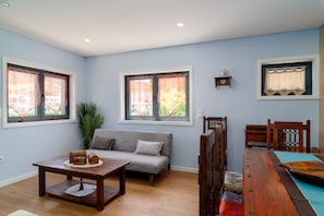 Una habitación con sofá, una mesa de madera y una mesa de comedor con sillas.