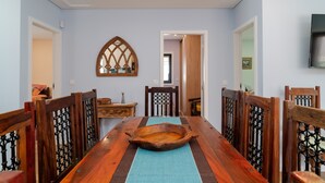 Un coin repas avec une table en bois, des chaises et un miroir décoratif au mur.