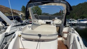 Un bateau à coque blanche, avec un pont en bois et un espace cabine équipé de sièges.