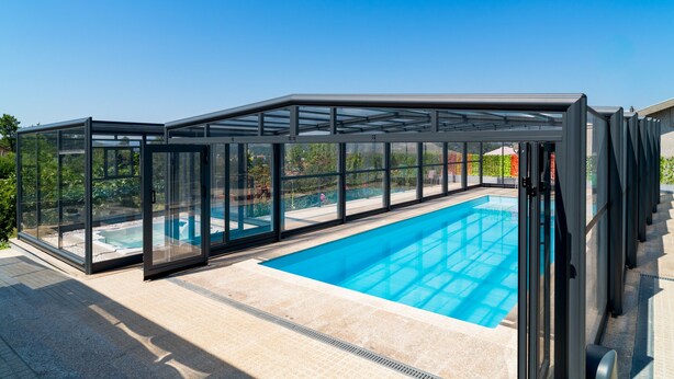 Une piscine dotée d’une enceinte en verre, un ciel dégagé et une vue sur les environs.
