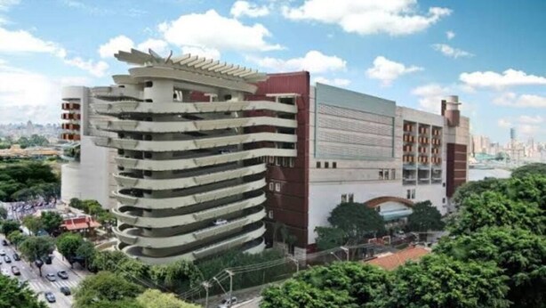 A multi-story building with a unique architectural design, featuring a curved facade and a rooftop structure. - Apto Allianz Metrô Barra Funda (Várzea da Barra Funda São Paulo)